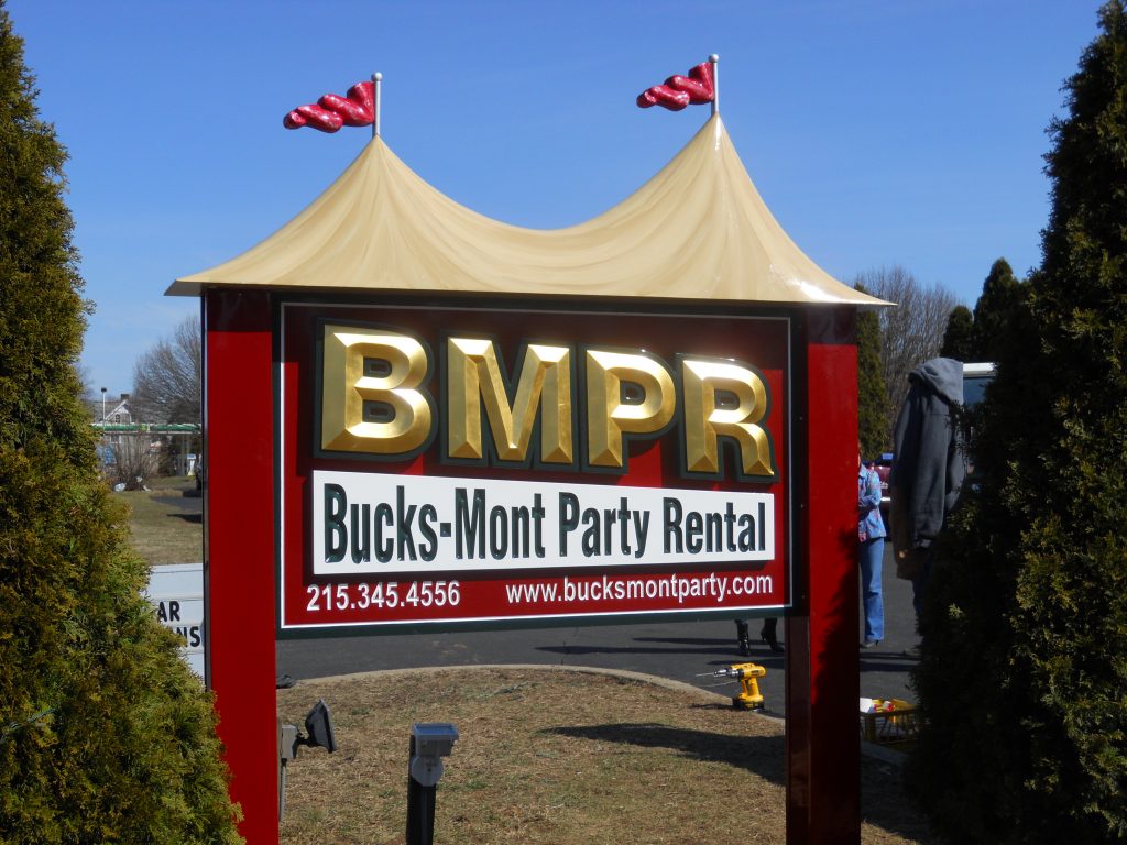 Bucks-Mont Party Rentals is a carved HDU 23kt. gold leafed sign with applied dimensional prizm letter & back panel. Hand carved tent & flag (SEE WORK IN PROGRESS)